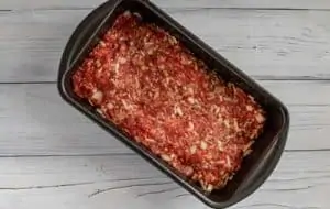 Photo of meatloaf in a dark loaf pan ready for the oven.