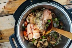 Second process shot of chicken being added to the Instant pot with the mushrooms, onion, and celery.