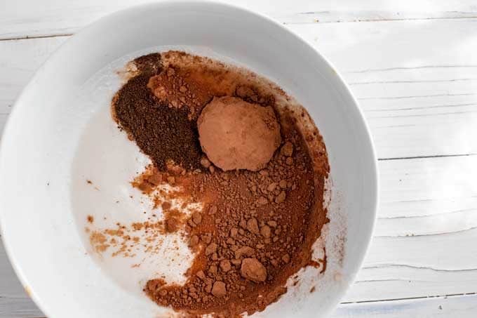 Photo of coconut milk, vanilla powder and unsweetened cocoa powder in a small white bowl.