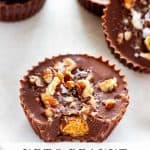 Close up photo of a keto peanut butter cup with a bite out of it and whole peanut butter cups behind it with a text overlay of the recipe title.