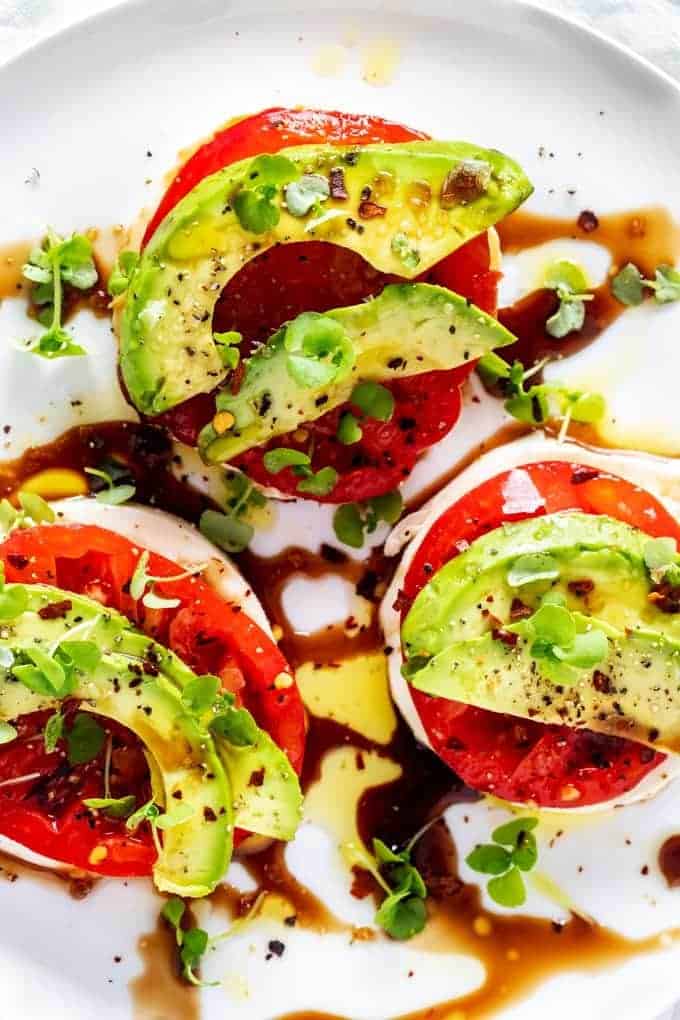 Overhead photo of a Keto Caprese Salad garnished with basil microgreens on a white plate.