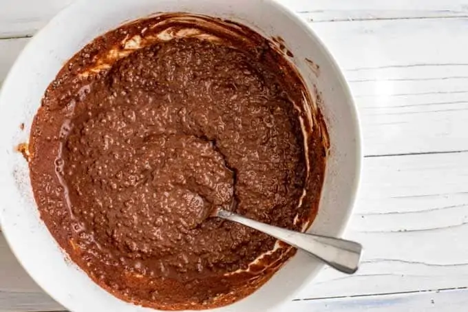 Photo of chocolate chia seed pudding that has just started to set in a small white bowl.