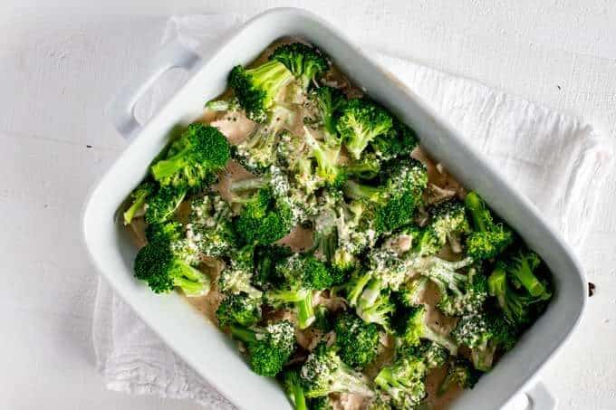 Photo of a creamy sauce that has been poured over chicken and broccoli in a casserole dish.
