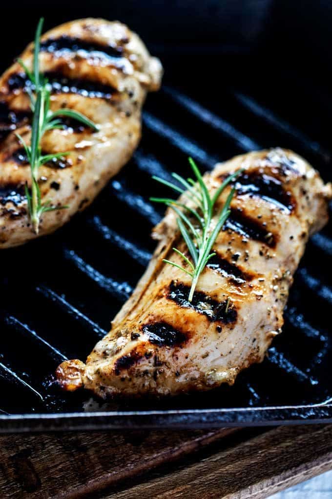 Photo of Keto Grilled Chicken in a cast iron grill pan garnished with rosemary.