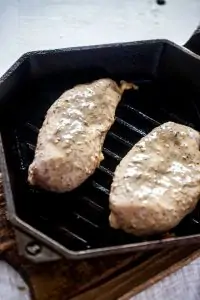 Photo of chicken breast cooking on a grill pan.