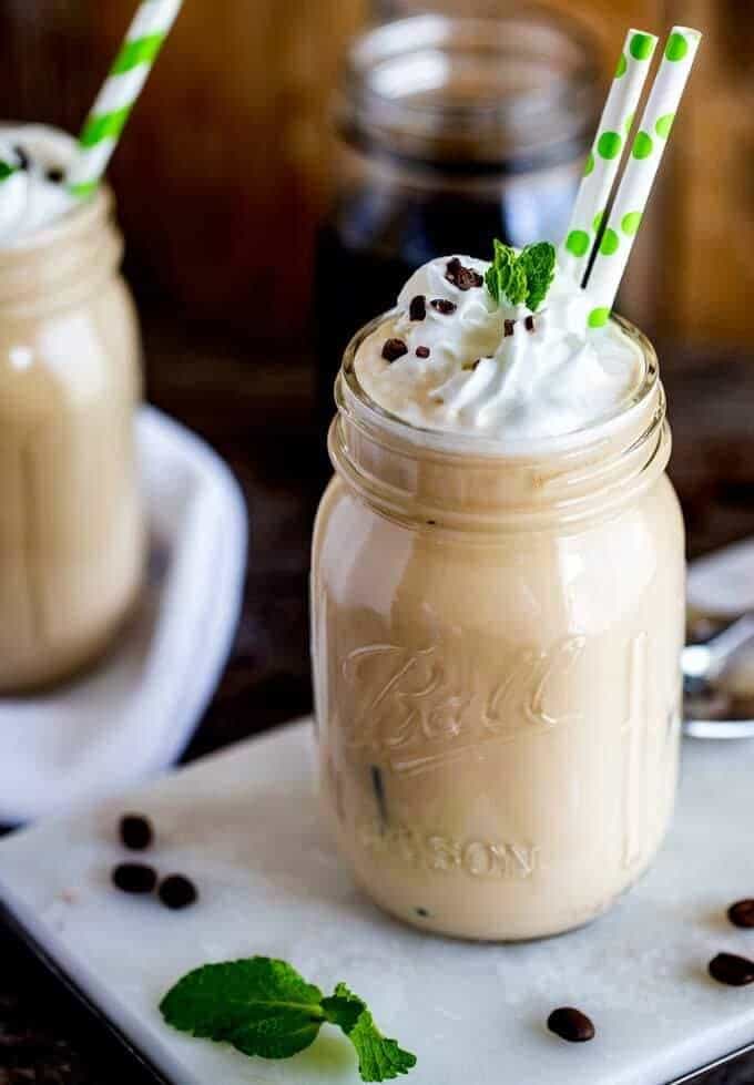 Photo of a Keto Iced Coffee in a mason jar with two straws and whipped cream on top.