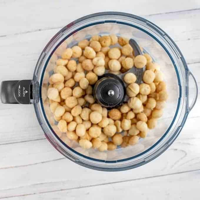 Photo of raw macadamia nuts in a food processor.
