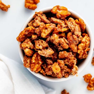 Overhead square photo of keto candied walnuts in a white dish.
