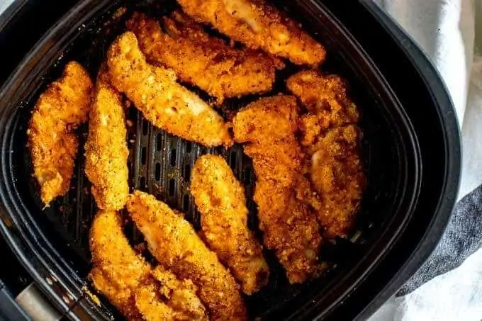 Photo of cooked chicken tenders in an air fryer.