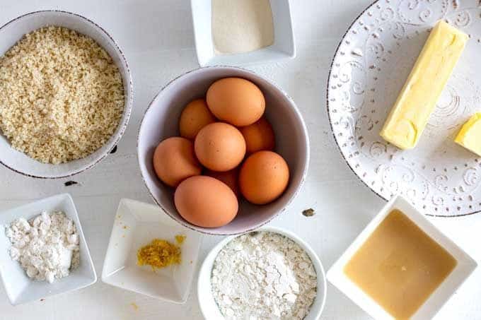 Photo of butter, macadamia nuts, Swerve confectioners, eggs, lemon juice, lemon zest, xanthan gum, and salt in white prep bowls.