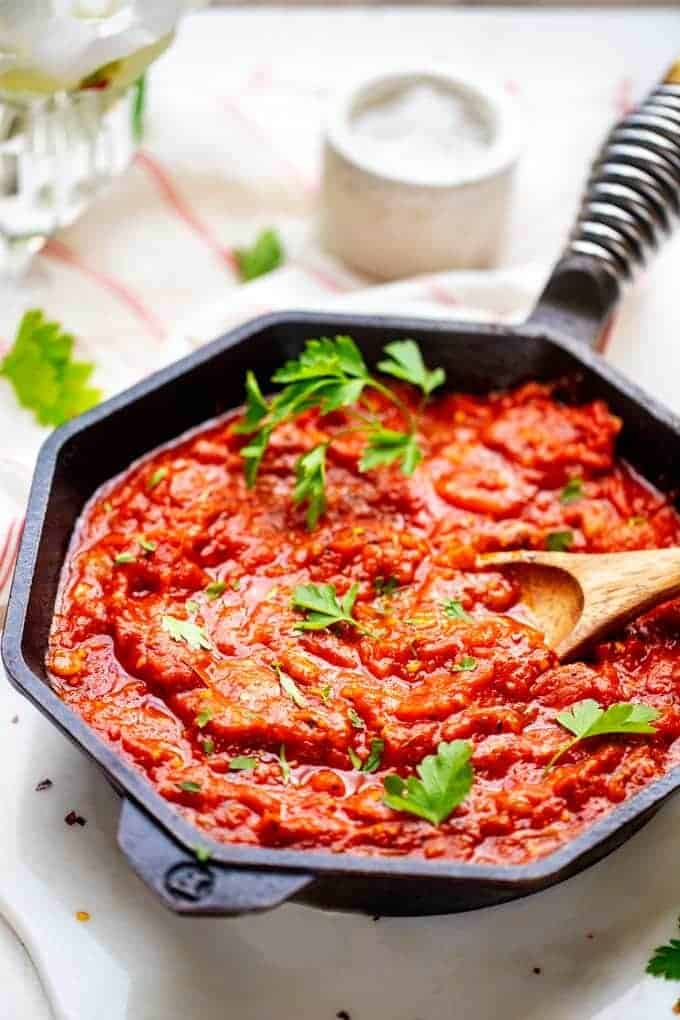 Photo of Low Carb Marinara in a large cash iron skillet with a wooden spoon in it garnished with parsley.