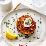Photo of keto Zucchini Fritters on a light great plate garnished with red onion, and parsley with the recipe title above it.