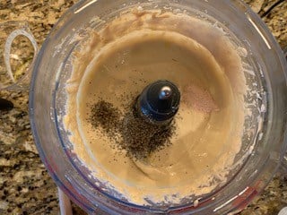 Photo of mayo, Parmesan, Dijon mustard, lemon juice, anchovy paste (or filets), and garlic in a food processor with salt and pepper added on top.