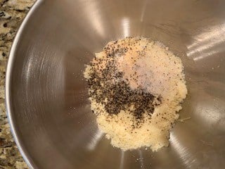 Photo of Parmesan, garlic powder, salt, and black pepper in a bowl.