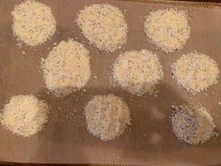 Photo of Parmesan, garlic powder, salt, and black pepper in small circles on a baking sheet.