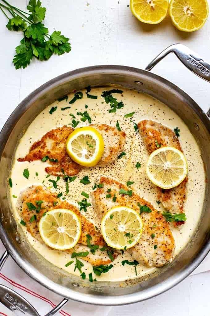 Photo of Keto Lemon Chicken in a large skillet garnished with parsley and lemons.