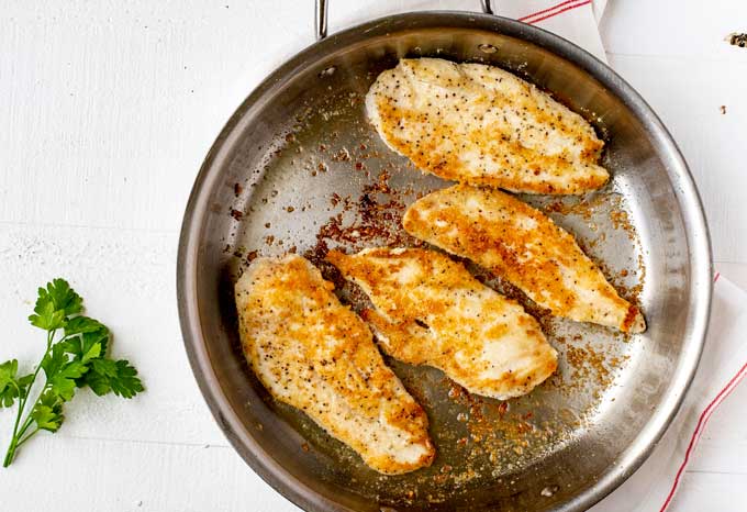 Photo of chicken being cooked in a large skillet.