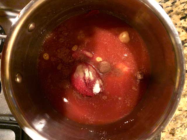 Photo of bone broth, tomato paste, apple cider vinegar, Swerve, garlic powder, onion powder, dry mustard, salt, cinnamon, and cayenne in a medium sauce pan.