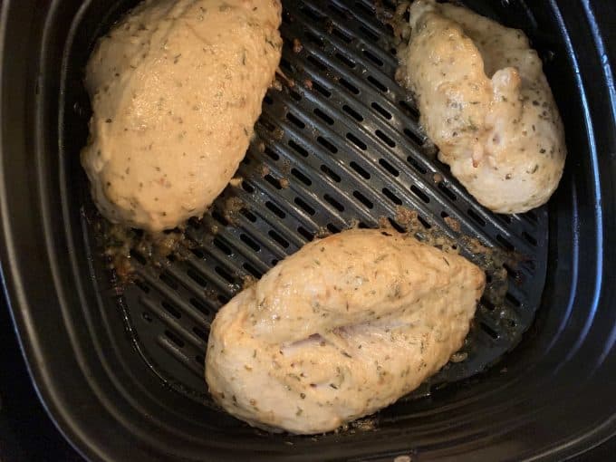 Photo of chicken that has cooked on one side and flipped cooking in an air fryer.