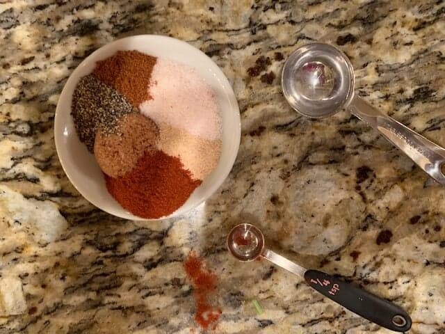 Photo of salt, brown sugar substitute, garlic powder, smoked paprika, black pepper and cayenne pepper in a small bowl.  