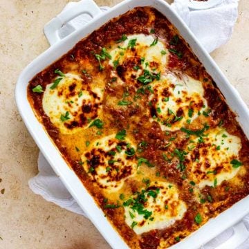 Overhead photo of keto lasagna in a white casserole dish garnished with parsley.