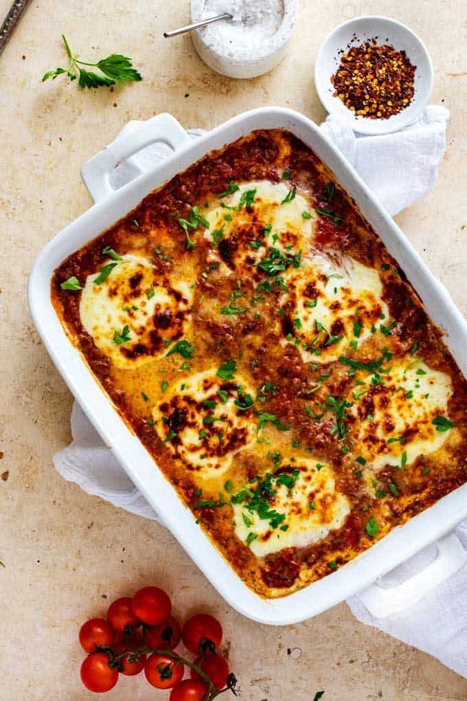 Overhead photo of keto eggplant lasagna in a white casserole dish garnished with parsley.