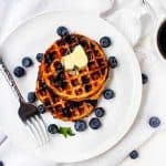 Square overhead image of Blueberry Chaffles on a white plate surrounded by blueberries.