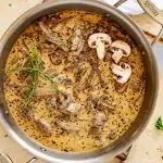 Square overhead photo of a large skilled of Keto Beef Stroganoff garnished with fresh thyme and mushrooms.