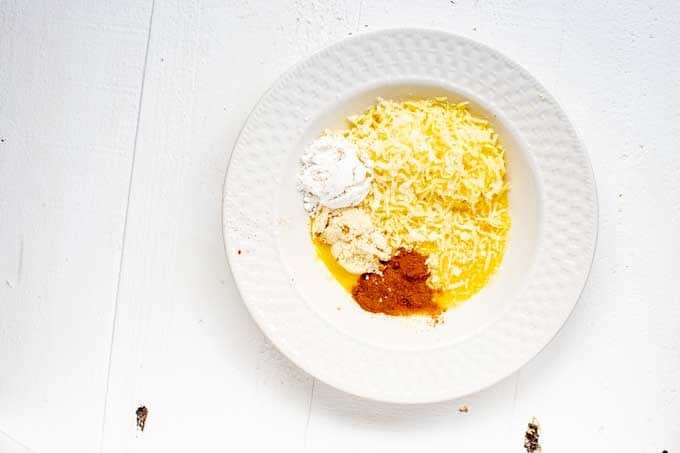 Photo of a white bowl with beaten egg, mozzarella cheese, almond flour, Swerve cinnamon, and vanilla.
