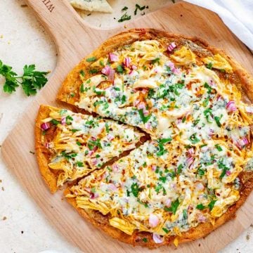 Overhead photo of a Keto Buffalo Chicken Pizza on a wooden pizza peel.