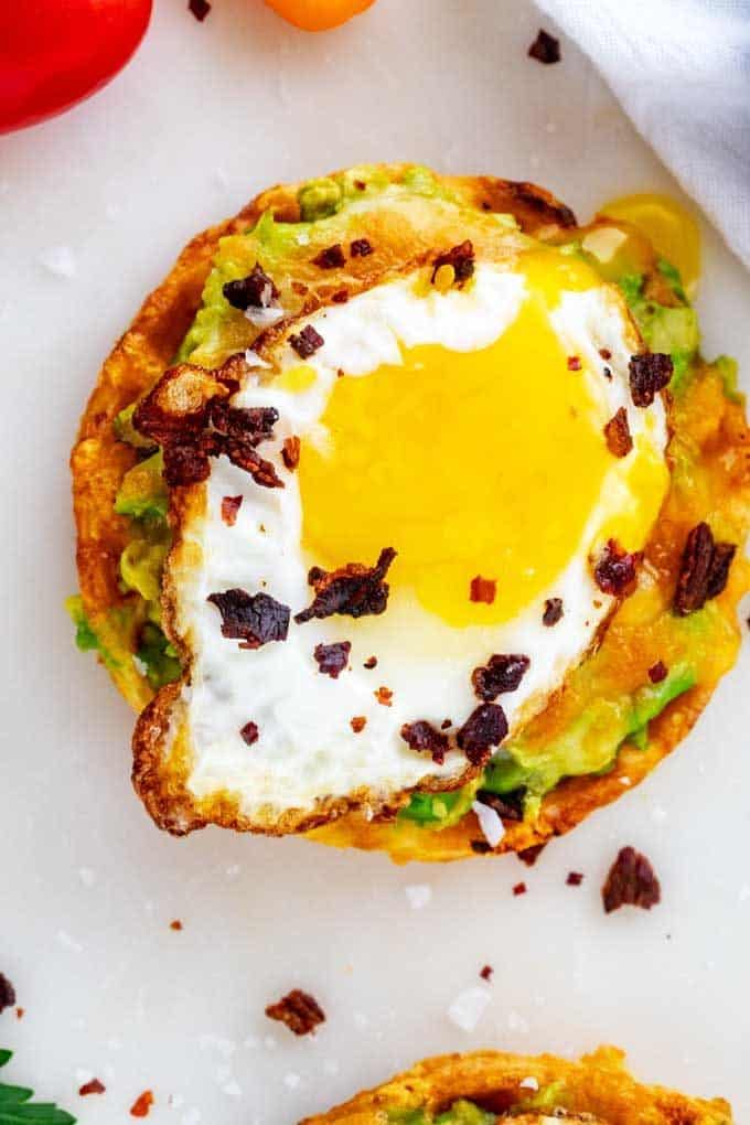 Overhead close up photo of Avocado Toast Chaffle with cheese, bacon, and a fried egg.