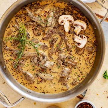 Overhead photo of a large skilled of Keto Beef Stroganoff garnished with fresh thyme and mushrooms.