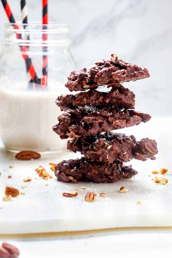Photo of five chocolate keto haystacks stacked on top of each other with a jar of almond milk behind it.