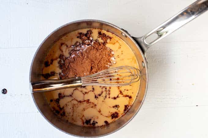 Photo of cocoa powder and sweetener added to a saucepan with melted coconut oil and peanut butter.