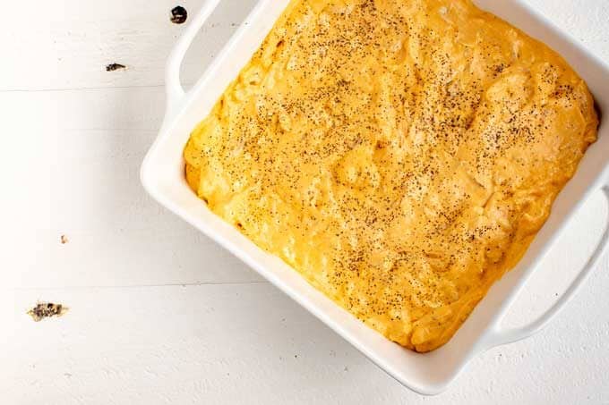 White 8 x 8 casserole dish with uncooked buffalo chicken dip.