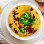 Square overhead photo of Keto Broccoli Cheese Soup in a white soup bowl garnished with broccoli, cheese, and bacon.