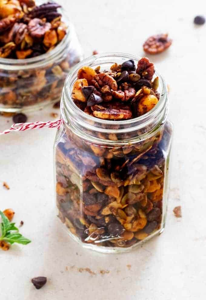 Side photo of two glass jars of keto trail mix on an off white background.