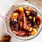 Overhead square photo of Keto Trail Mix in a glass jar with trail mix scattered below.