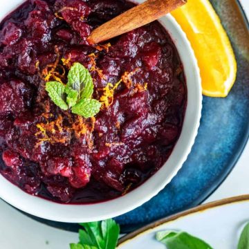 Overhead photo of a bowl of keto cranberry sauce garnished with mint and oranges.