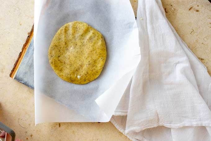 Photo of fathead pizza dough that has been formed into a disk on a sheet of parchment paper.