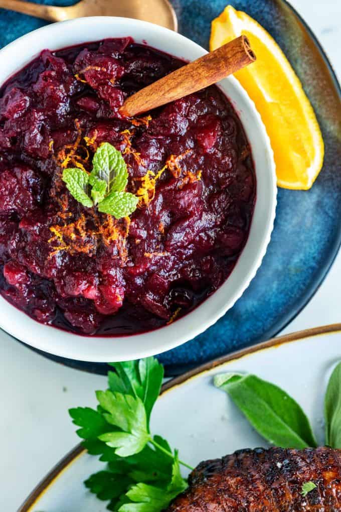 Overhead photo of a bowl of keto cranberry sauce garnished with mint and oranges.