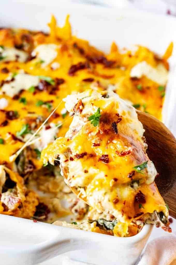 Close up photo of a spoonful of Keto Chicken Bacon Ranch Casserole garnished with parsley with a cheese pull.