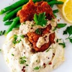 Close up square photo of Low Carb Chicken Fried steak sitting on a bed of mashed cauliflower and green beans.