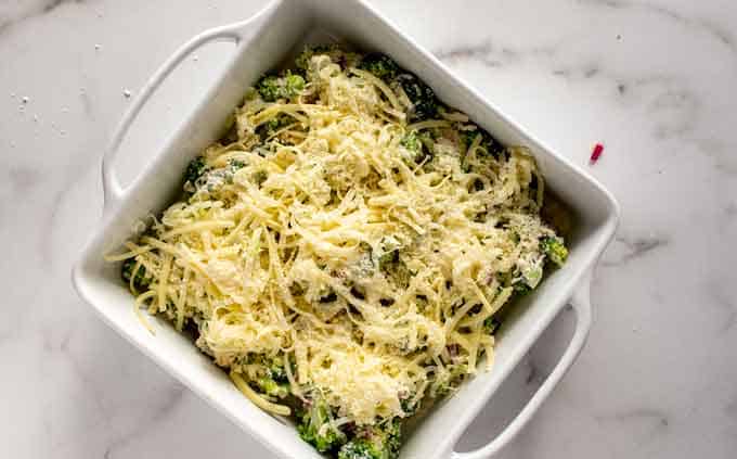 Photo of broccoli in a creamy sauce covered in cheese in a white casserole dish.