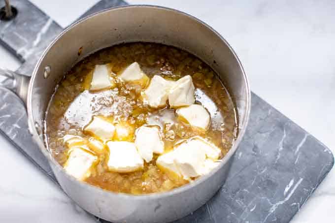 Photo of cream cheese cubes in a pot of soup.