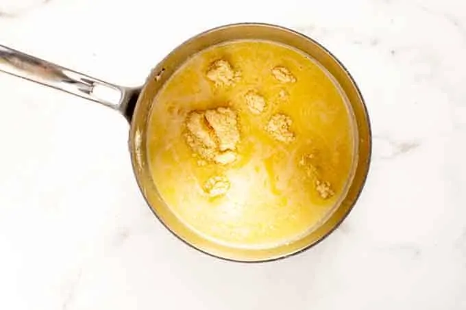 Photo of Parmesan being added to a saucepan of butter, heavy cream, and broth.