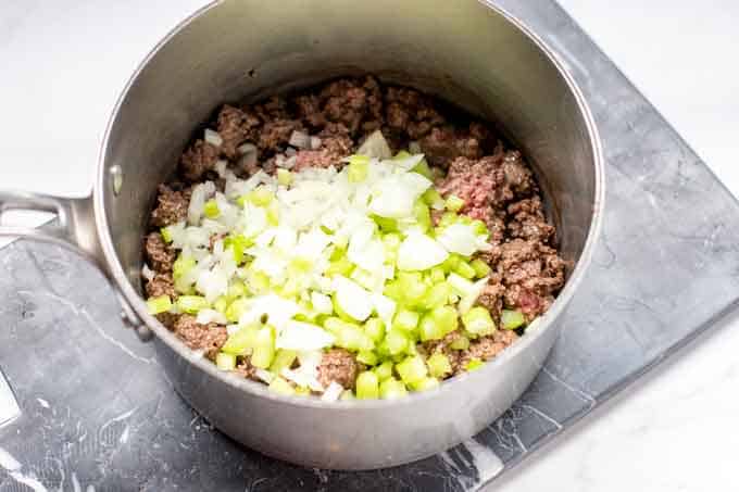 Photo of ground beef that is browned in a pot that has just had onion and celery added to it.