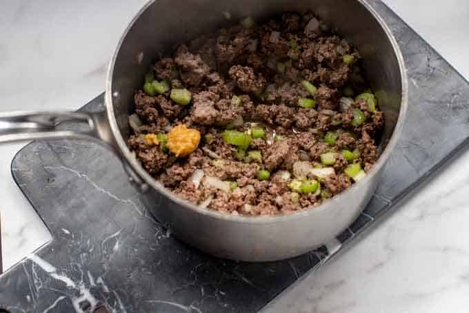 Photo of ground beef, onion, celery, and seasonings in a pot.