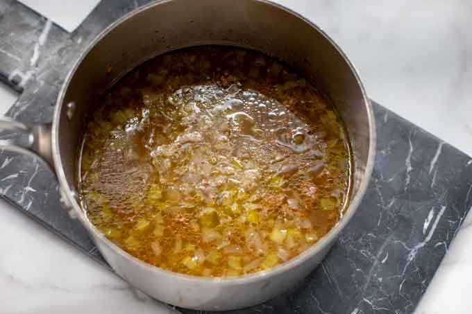 Photo of broth being added to a pot of ground beef, onion, celery, garlic, and seasonings.