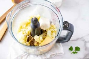 Photo of steamed cauliflower, cream cheese, and seasonings in a food processor.